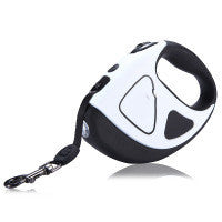 A hand holding a retractable dog leash with an LED shining button, predominantly black and white in color.