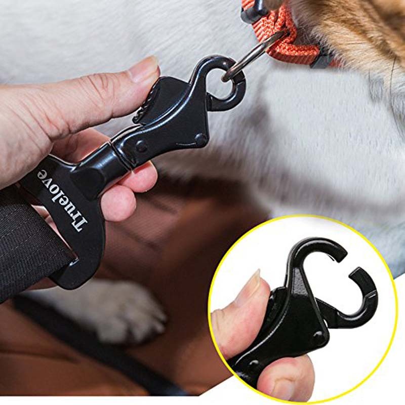 A black dog seat belt made of aluminum, being fastened onto a dog's collar by a person.