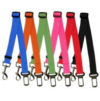A collection of adjustable car safety belts for dogs in various colors, shown attached to a pet harness and secured in a vehicle seatbelt slot.