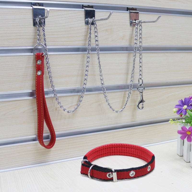 A metal traction chain for dogs with a PU handle, displayed on a wooden floor alongside a purple flower.