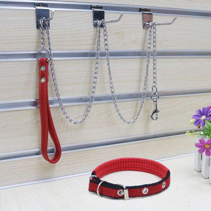 A metal traction chain for dogs with a PU handle, displayed on a wooden floor alongside a purple flower.