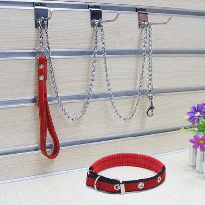 A metal traction chain for dogs with a PU handle, displayed on a wooden floor alongside a purple flower.